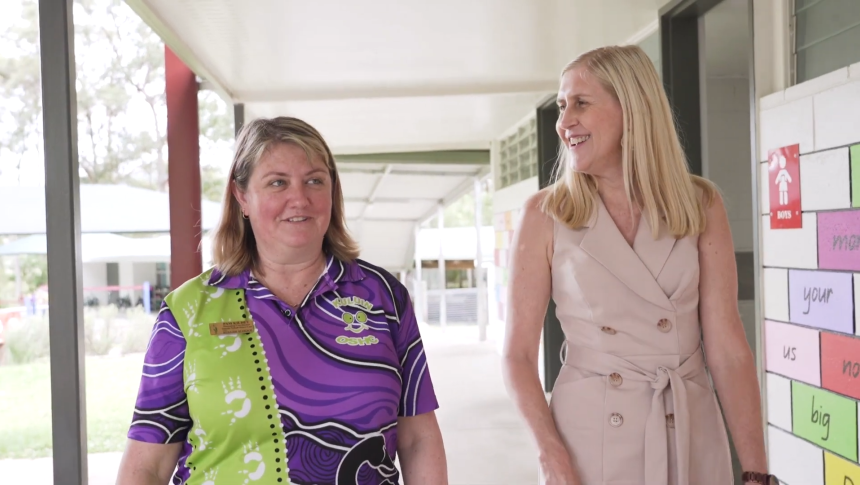 Two female teachers walking in undercover area outside school classroom