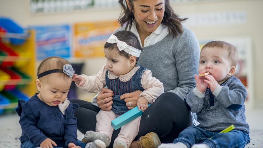 Educator sitting with 3 toddlers