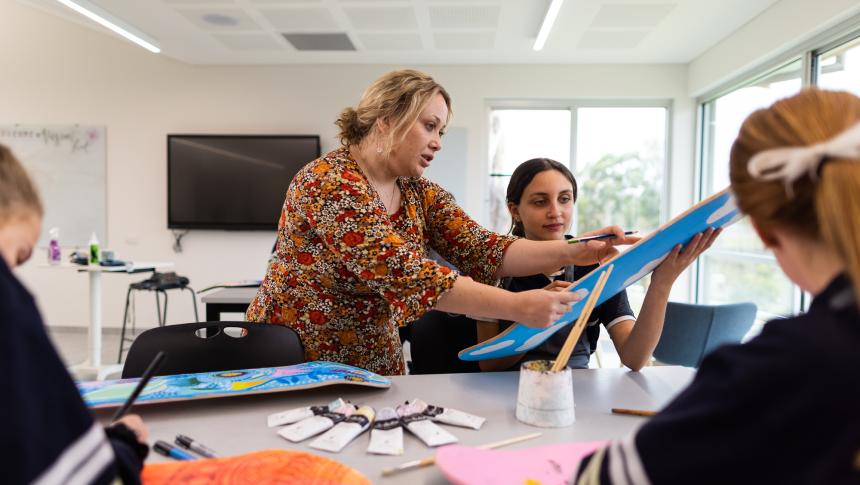 Teacher helping students with artwork