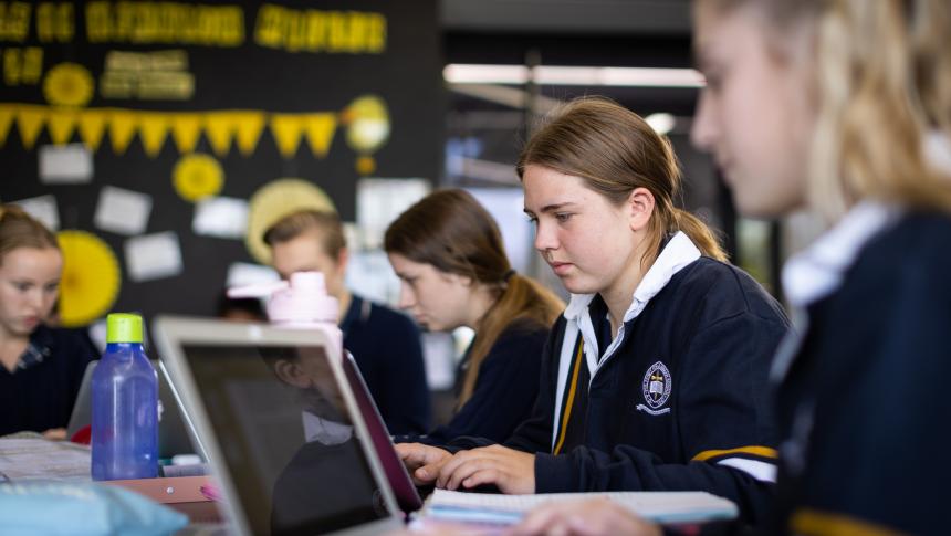 Students sitting at their desks using laptops