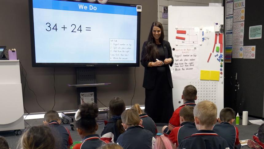 Teacher in front of a screen giving a lesson to a class of primary school students