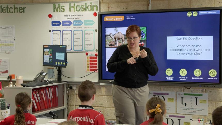 Teacher in front of a screen giving a lesson to a class of primary school students